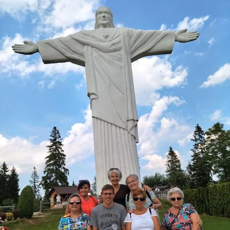 statue of Jesus in a small Orava village Klin. On the photo tour guide posing with the elderly clients from Spain