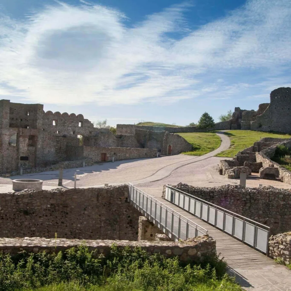Devín Castle ruins near Bratislava, a historic landmark on a private wine city break Bratislava tour, featuring ancient stone walls, modern wooden walkway, and scenic walking paths under blue skies