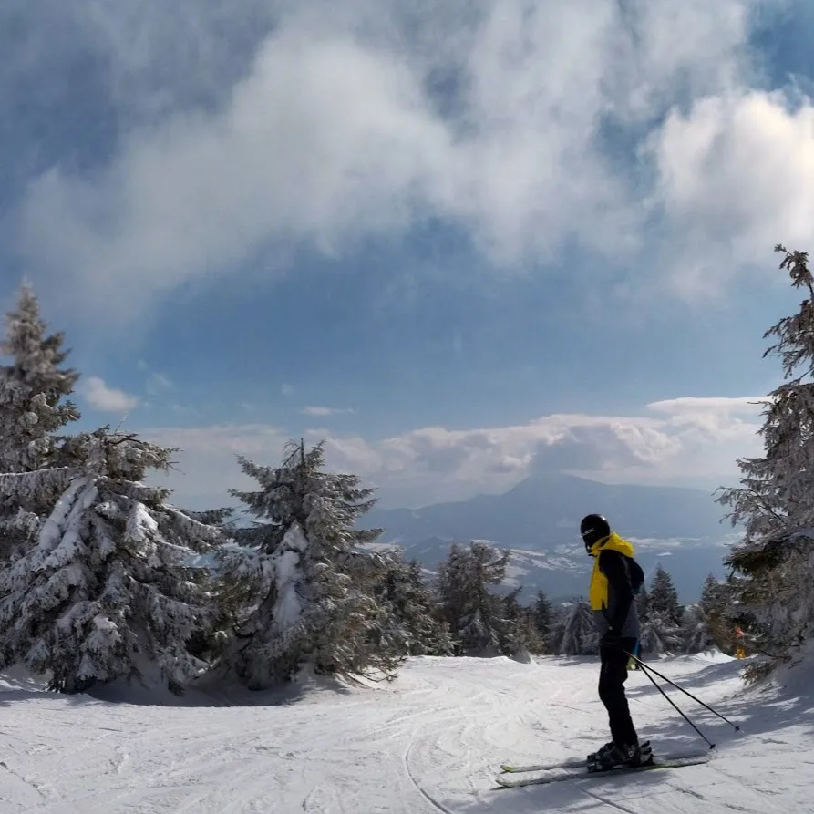 Skier at the summit of Kubínska Hoľa ski resort in Orava, Slovakia, with frost-covered spruce trees and a transmitter tower
