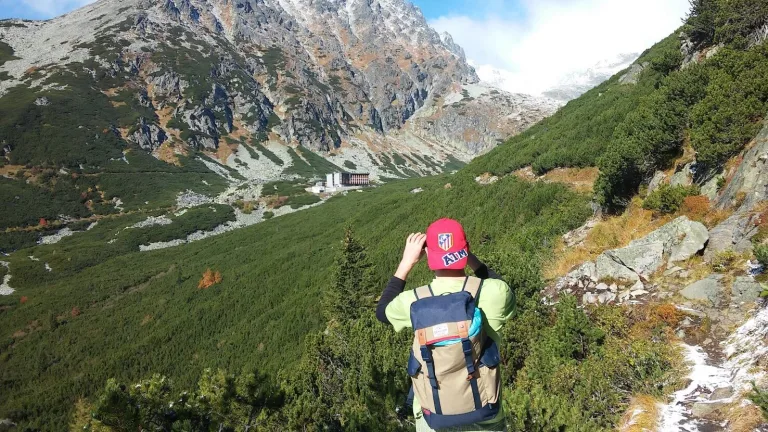 A walker with a backpack on a path through a High Tatras valley, the rocky peaks rising ahead.
