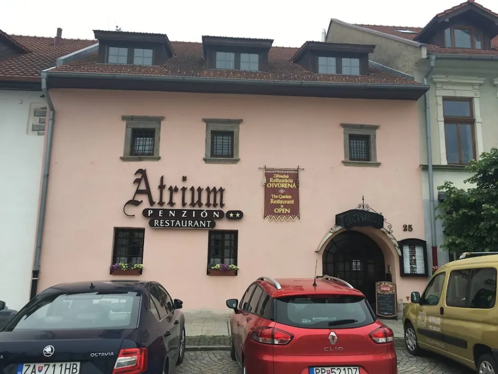The Atrium pension and restaurant in a High Tatras resort village, cars parked on the street outside.