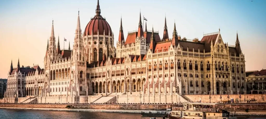 The Hungarian Parliament on the Danube embankment in Budapest, lit by the late afternoon sun.