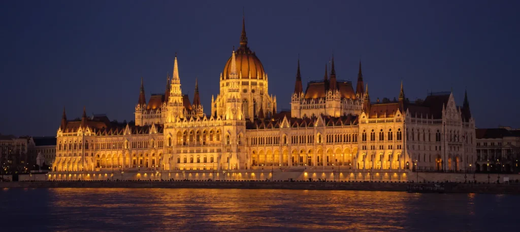 The Hungarian Parliament in Budapest floodlit after dark, reflected in the Danube.