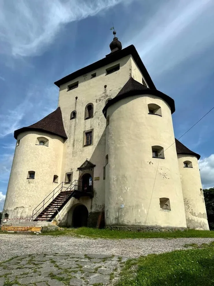 The white New Castle above Banská Štiavnica, its four round corner bastions and steep shingled roofs against a blue sky.