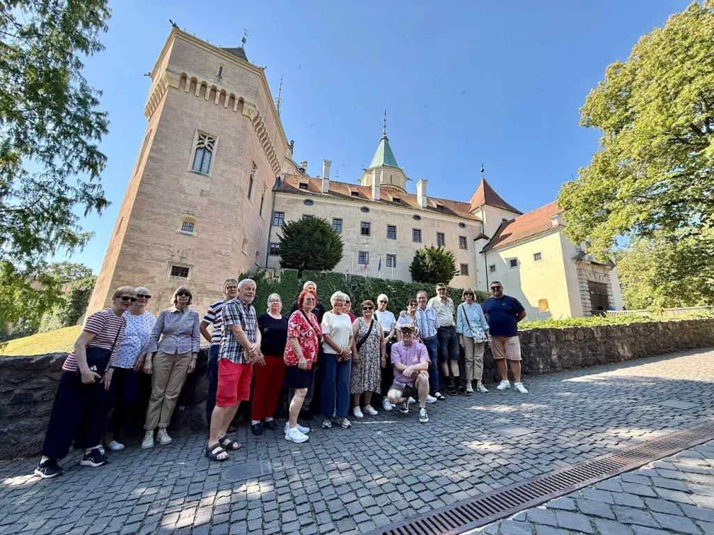 Un groupe de touristes posant devant le château de Bojnice en Slovaquie par une journée ensoleillée.