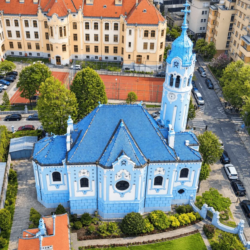 The Blue Church of St Elizabeth in Bratislava from the air, its blue tiled roof and round tower rising above the surrounding streets.