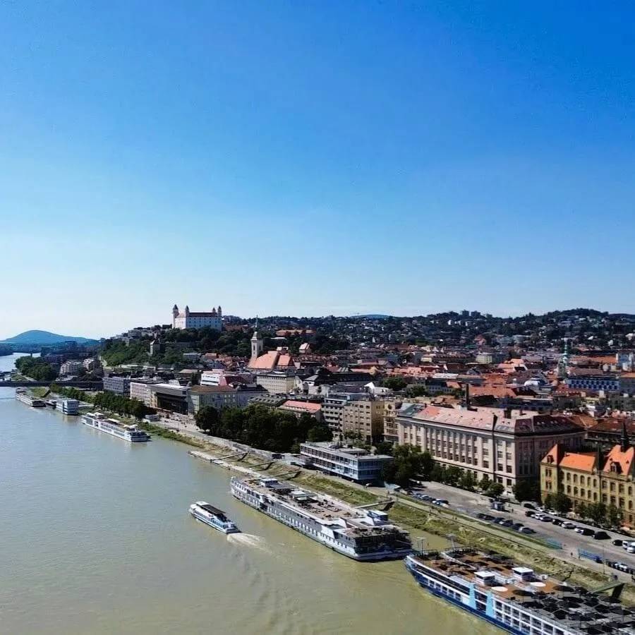 River cruise boats moored along the Danube in Bratislava, with the castle on the hill above the old town.