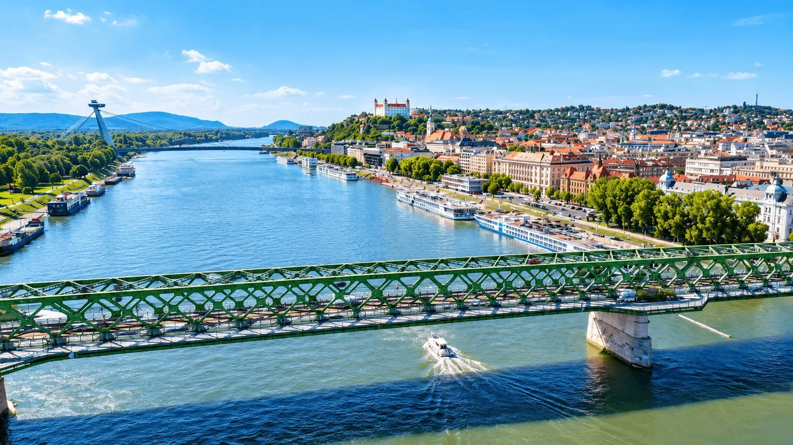El Danubio a su paso por Bratislava, con el puente antiguo, cruceros fluviales junto al muelle y el castillo sobre el casco antiguo.