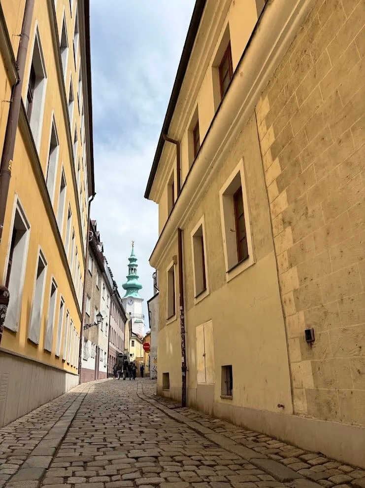 A narrow cobbled lane in Bratislava's old town leading to the green tower of St Michael's Gate.