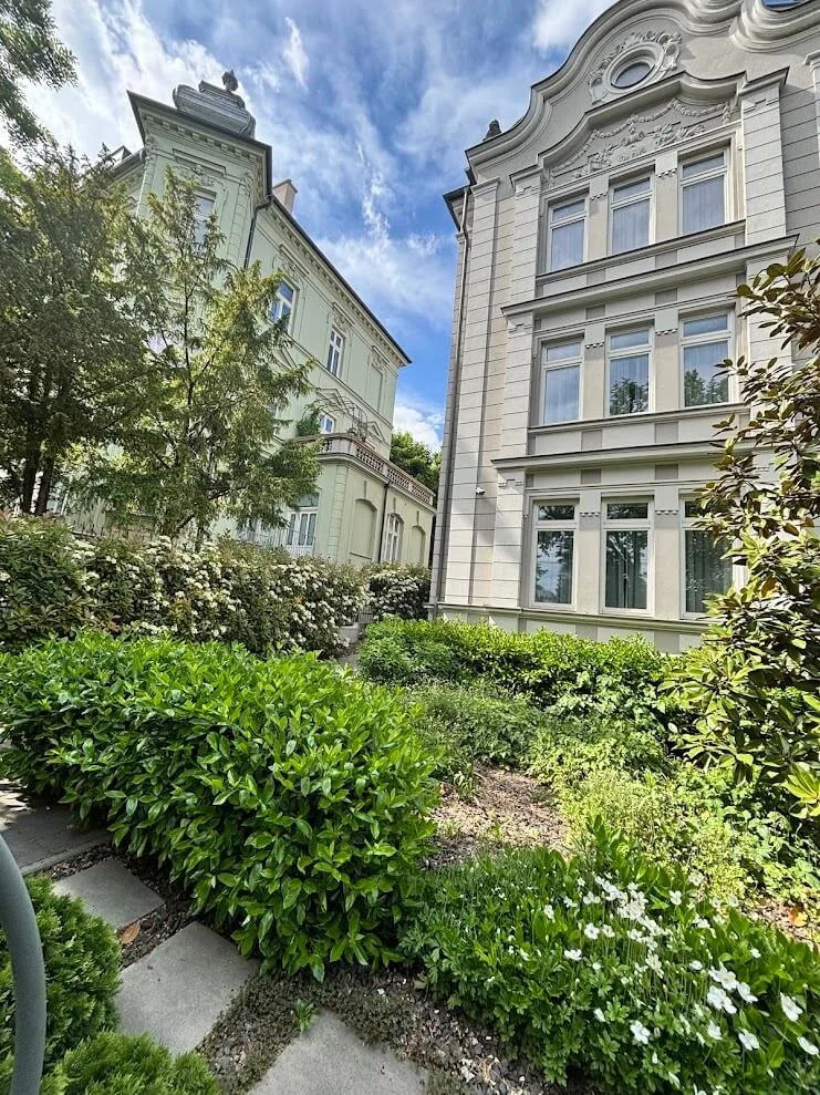 A quiet street of restored villas in Bratislava, with clipped hedges and planted gardens in front.