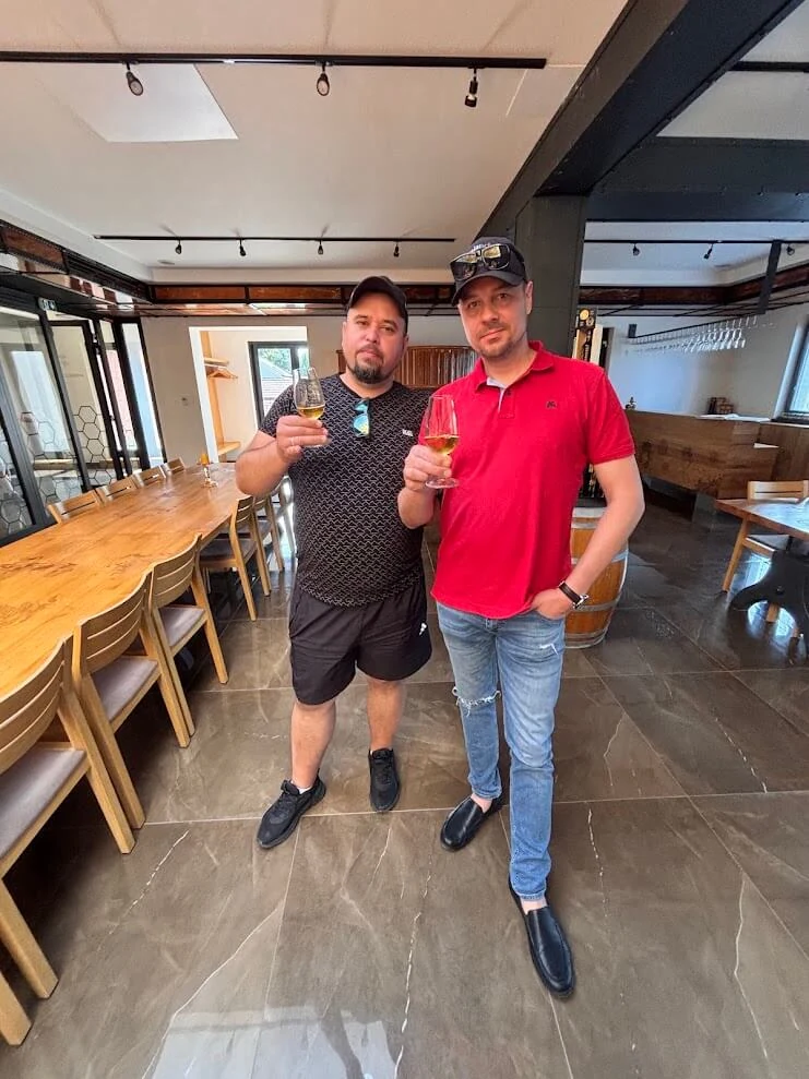 Two visitors raising glasses of mead in the light-filled tasting room of a mead producer at Dolná Krupá.