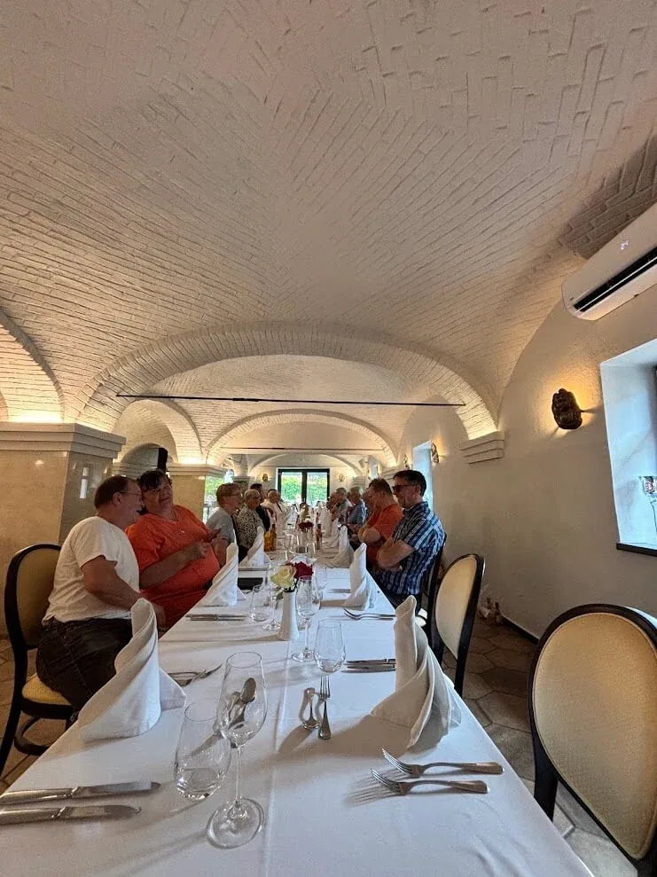 A long table laid with white linen for a group dinner in a whitewashed vaulted cellar restaurant at Dolná Krupá.