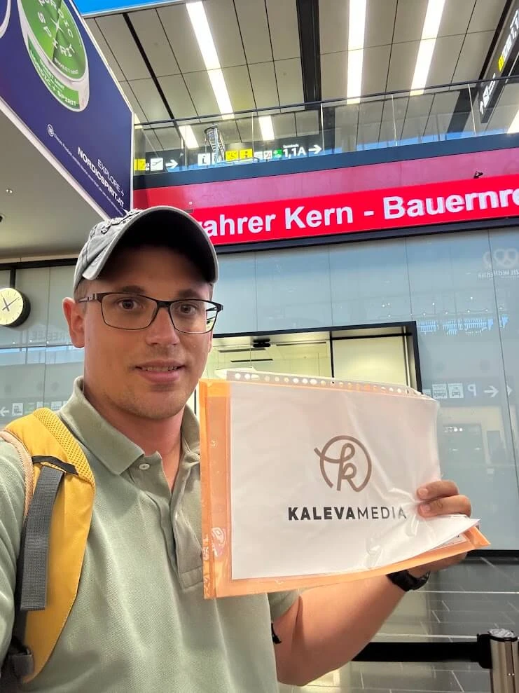 Andrej Stanik con un cartello con il nome per dare il benvenuto ai suoi ospiti nella sala arrivi di un aeroporto.