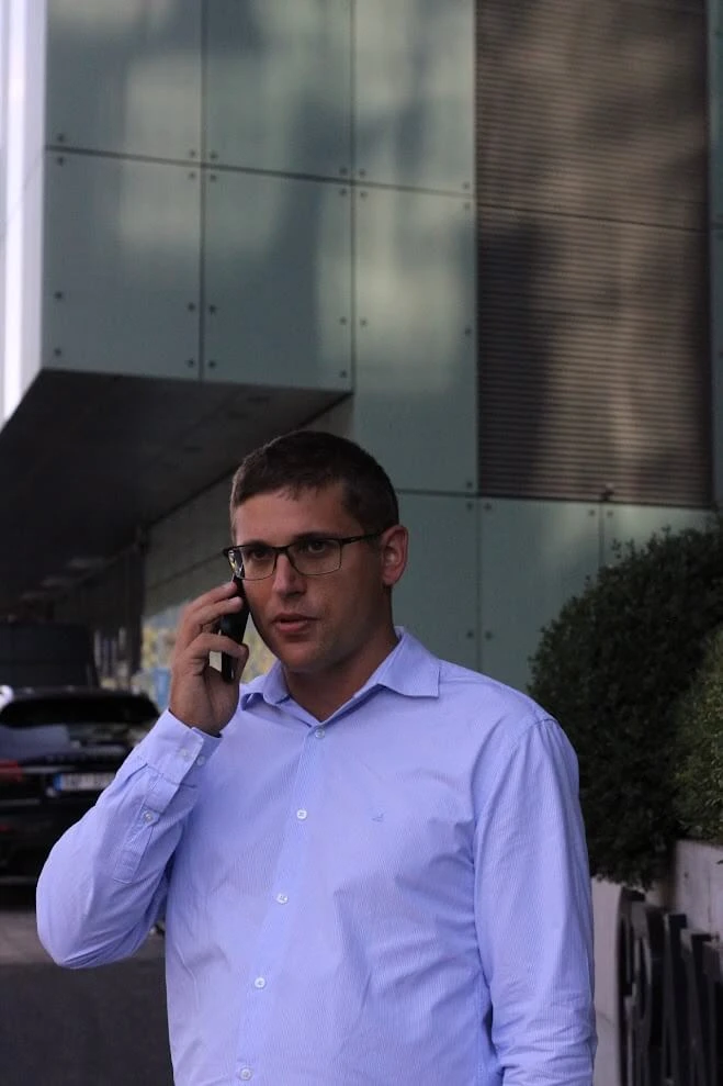 Andrej Stanik al telefono davanti a un moderno edificio per uffici.