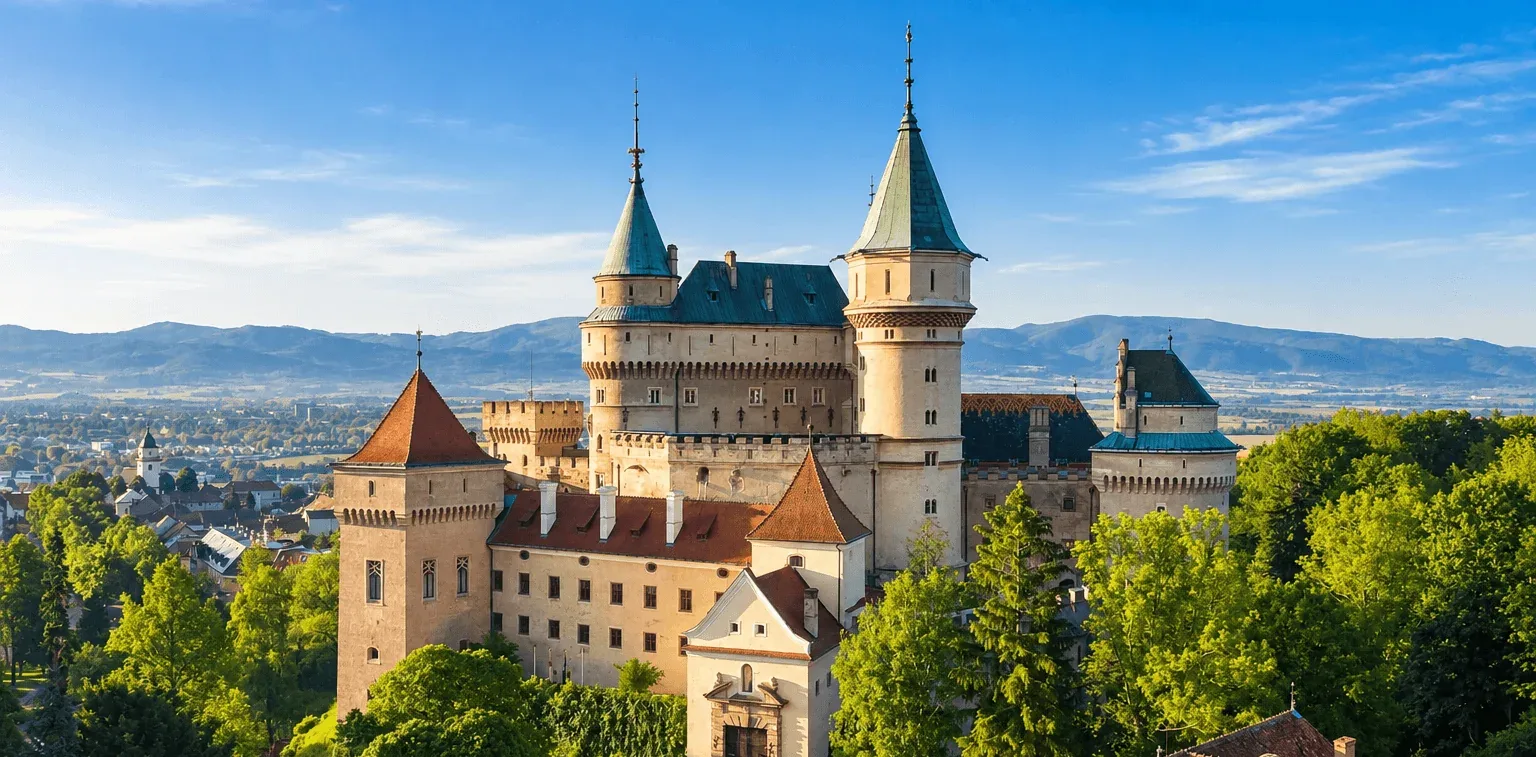 Bojnice Castle rising above the trees, with its towers and turrets and the hills of the Upper Nitra valley behind.