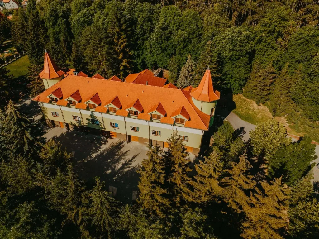 An aerial view of a spa building with orange roofs and corner turrets among the trees at Bojnice.