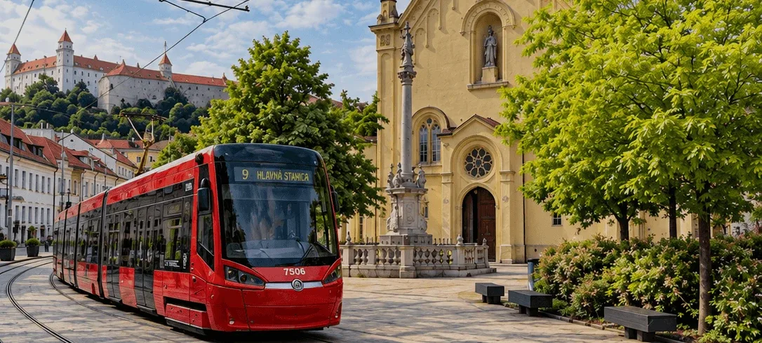 Un tram rosso che passa davanti alla chiesa dei Cappuccini e alla sua colonna mariana su Župné námestie a Bratislava, con il castello di Bratislava sulla collina alle spalle.