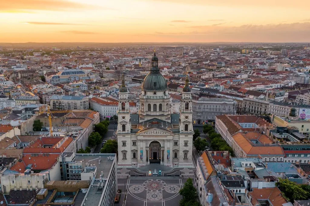 St Stephen's Basilica and the rooftops of central Budapest seen from the air at sunset, with the patterned paving of the square laid out in front of it.