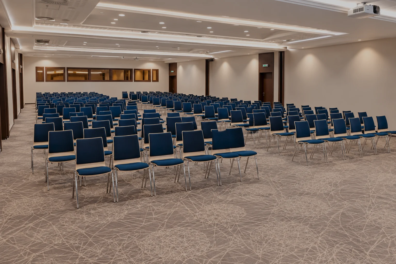 Une salle de conférence aménagée en style théâtre, avec des rangées de chaises bleues, prête pour un congrès.