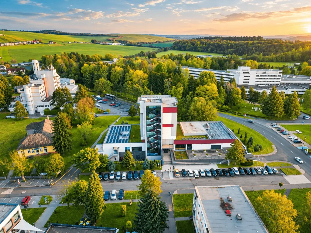 An aerial view of the spa in Dudince at sunset, with spa hotels among the trees and rolling fields beyond.