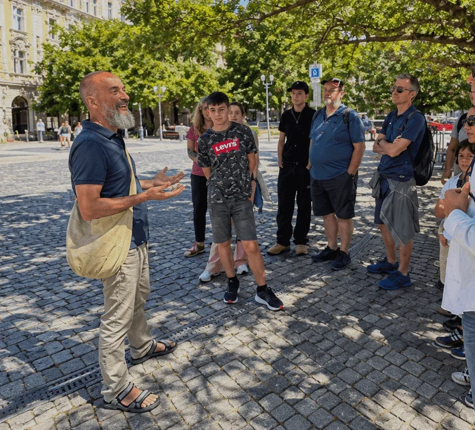 Una guida locale che conduce un tour a piedi per un piccolo gruppo in una piazza ombreggiata dagli alberi nella Città Vecchia di Bratislava.