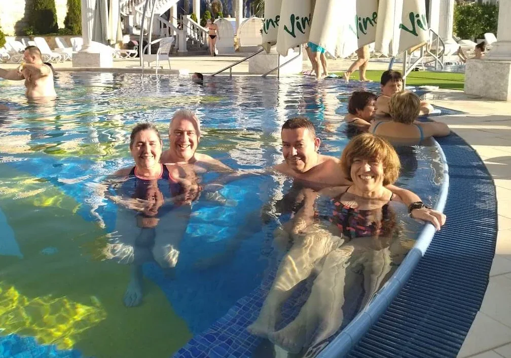 Гости отдыхают в открытом термальном бассейне курорта Aphrodite в Раецке-Теплице среди белых колонн и балюстрад.