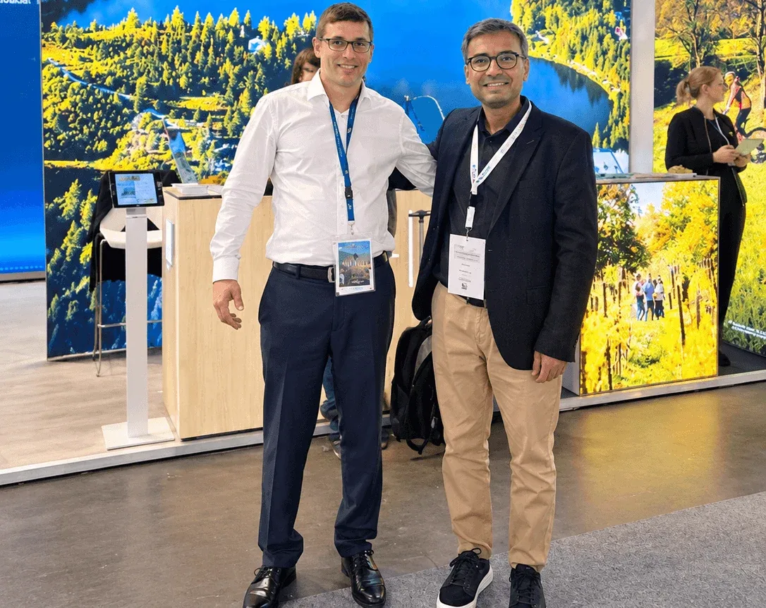 Due persone allo stand della Slovacchia a una fiera del turismo professionale, davanti a una grande foto di un lago di montagna.