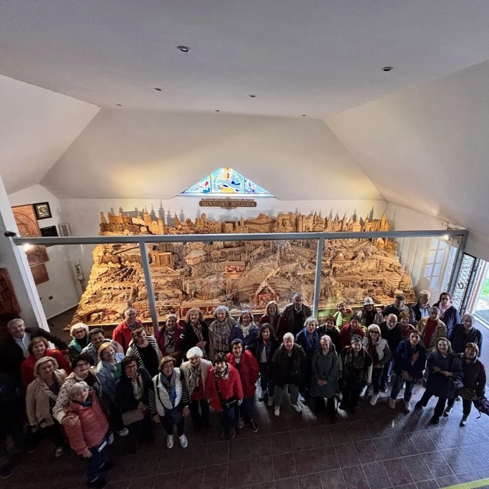 A tour group gathered in a church in front of a tall carved and gilded wooden altar.
