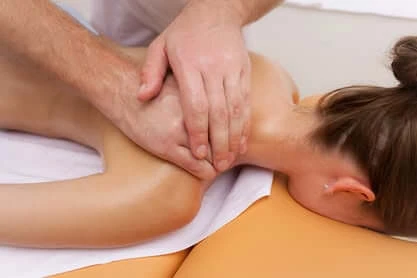 A therapist massaging a spa guest's neck and shoulders during a treatment.