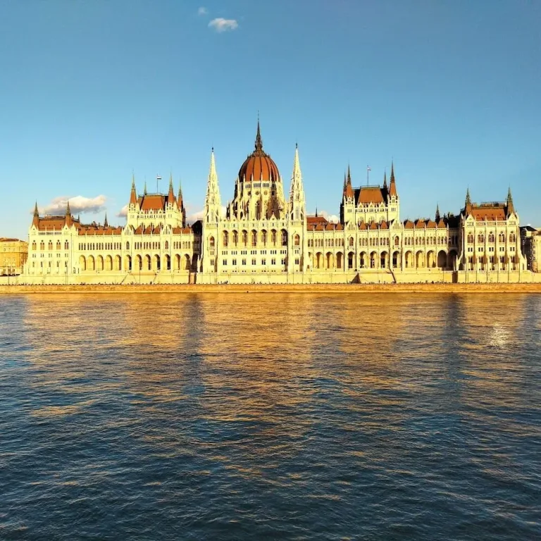 The Hungarian Parliament Building in Budapest lit gold by low sun, seen from across the Danube.