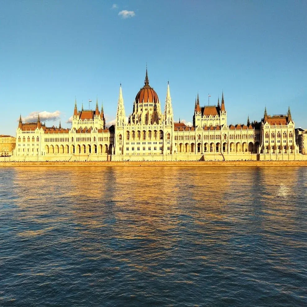 The Hungarian Parliament Building in Budapest lit gold by low sun, seen from across the Danube.