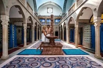 A couple by the fountain inside the Hammam bathhouse in Trenčianske Teplice, beneath its Moorish arches and tiled walls.
