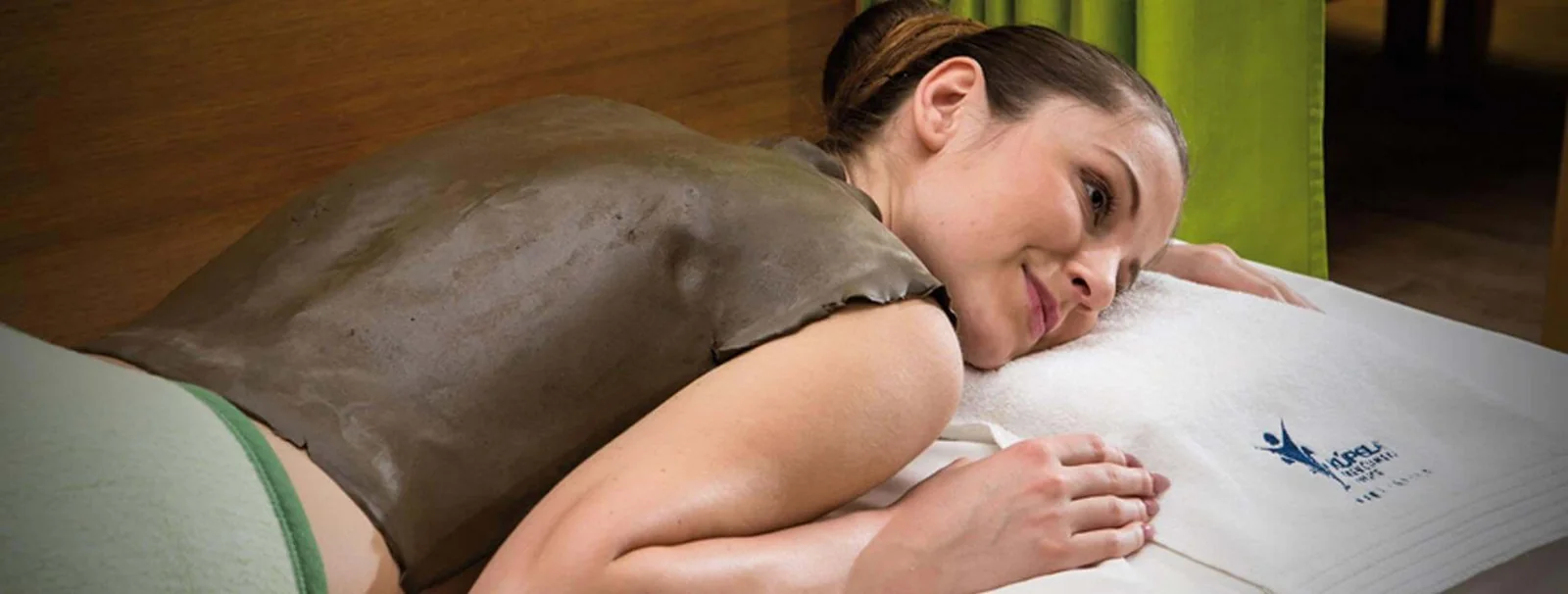 A guest resting during a healing mud wrap on her back, on a Kúpele Trenčianske Teplice towel.