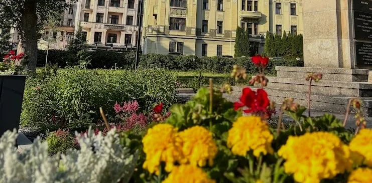 Marigolds and red geraniums in bloom in the spa park at Trenčianske Teplice, with a yellow historic spa building behind.