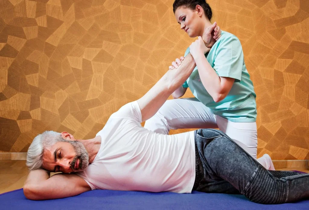 A therapist guiding a guest through an assisted stretch on a mat at the spa in Turčianske Teplice.