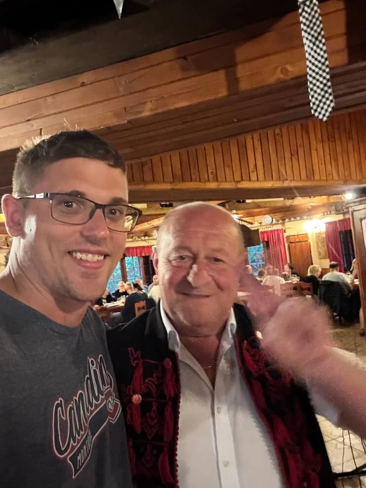 A guest with the host of a folklore evening in the High Tatras, who wears a traditional Slovak waistcoat embroidered in red.