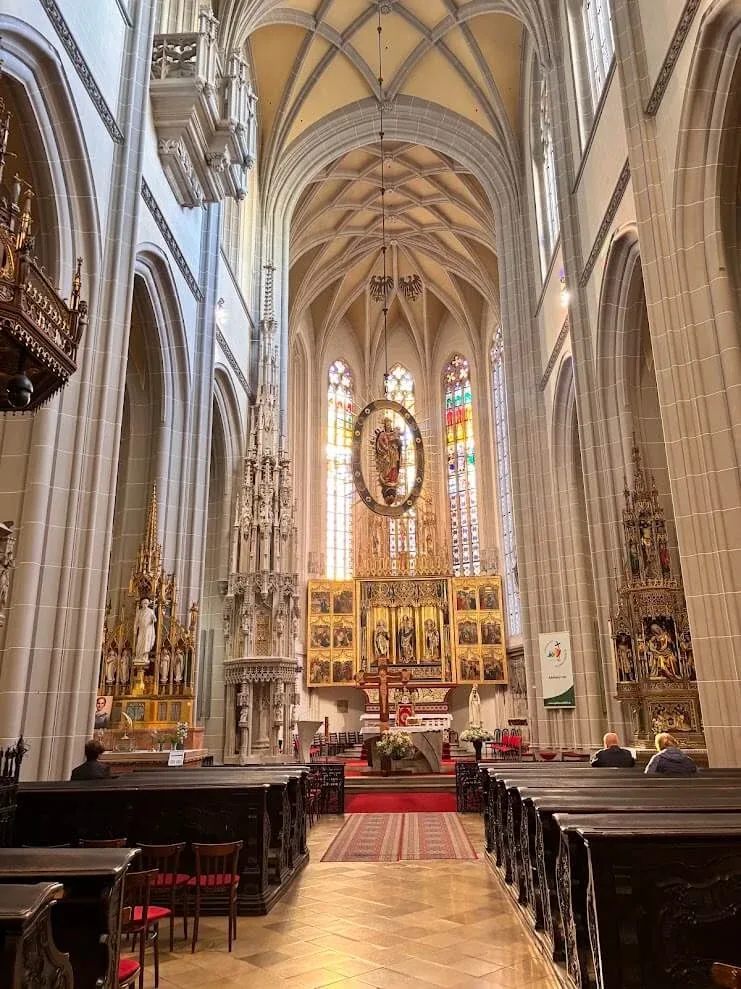 The Gothic nave of St Elisabeth Cathedral in Košice, looking down the aisle to the gilded high altar and the stained-glass windows above it.