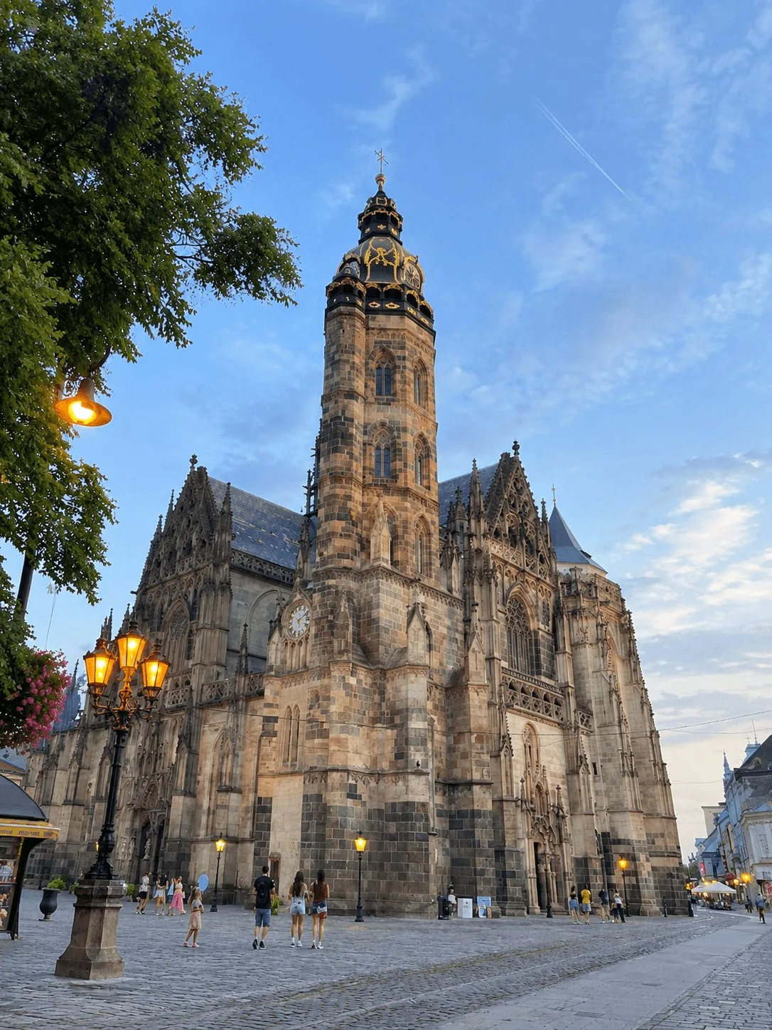 La cathédrale Sainte-Élisabeth de Košice au crépuscule, la plus grande église de Slovaquie, sa tour gothique illuminée au-dessus de la rue principale et des lampes allumées sur la place.