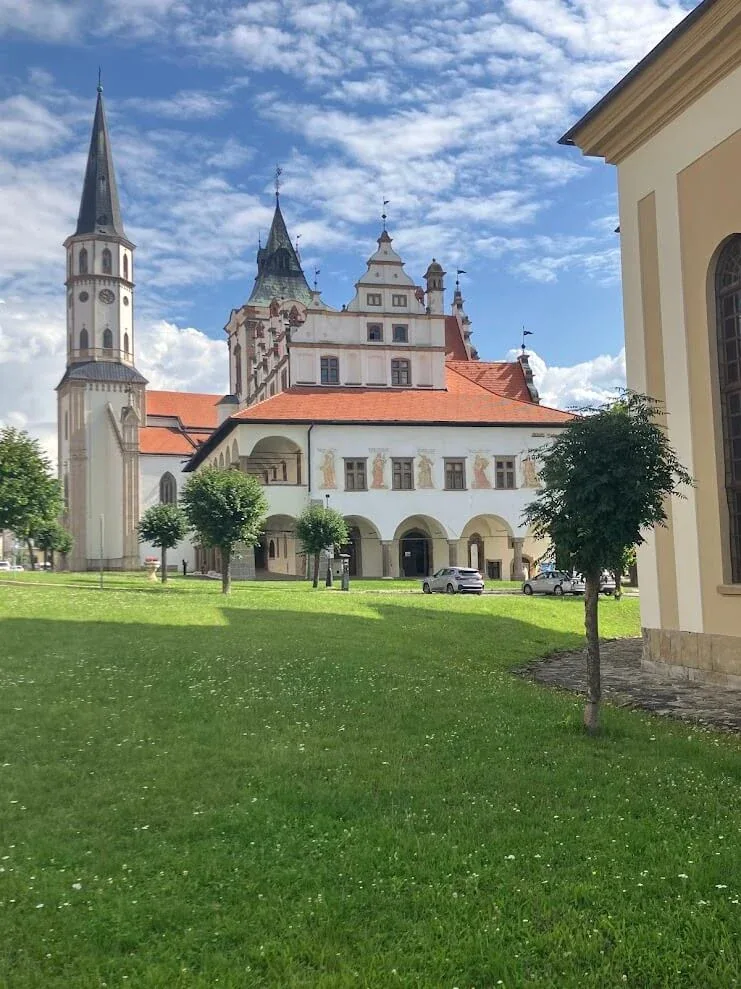 The spire of St James's Church and the gabled town hall of Levoča seen across the lawn of the main square.
