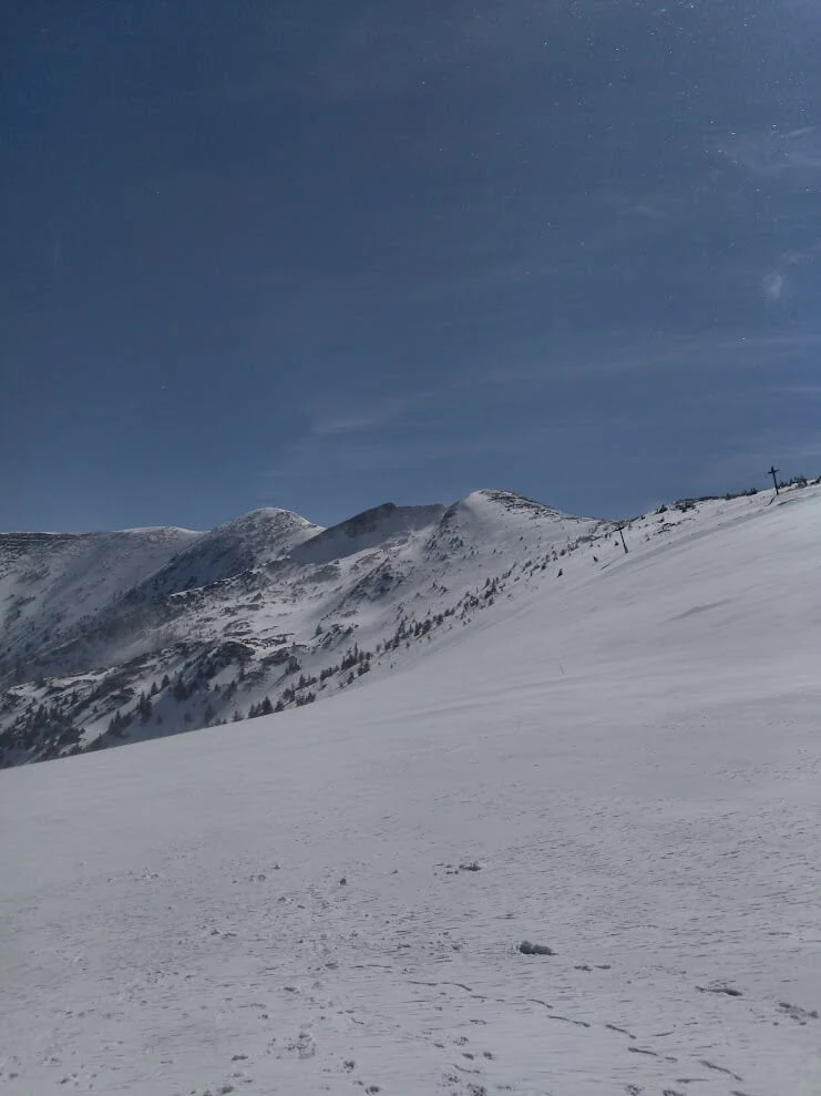 A broad snow-covered slope running up to the ridge of the Malá Fatra under a deep blue winter sky.