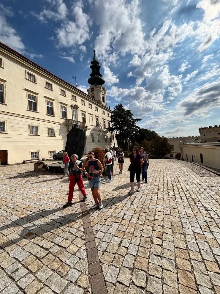Visitors crossing the cobbled courtyard of Nitra Castle, the bishop's palace on the left and the cathedral tower behind.