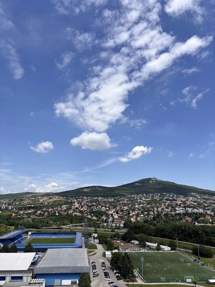 A view across the rooftops of Nitra to the wooded summit of Zobor Hill under a wide blue sky.