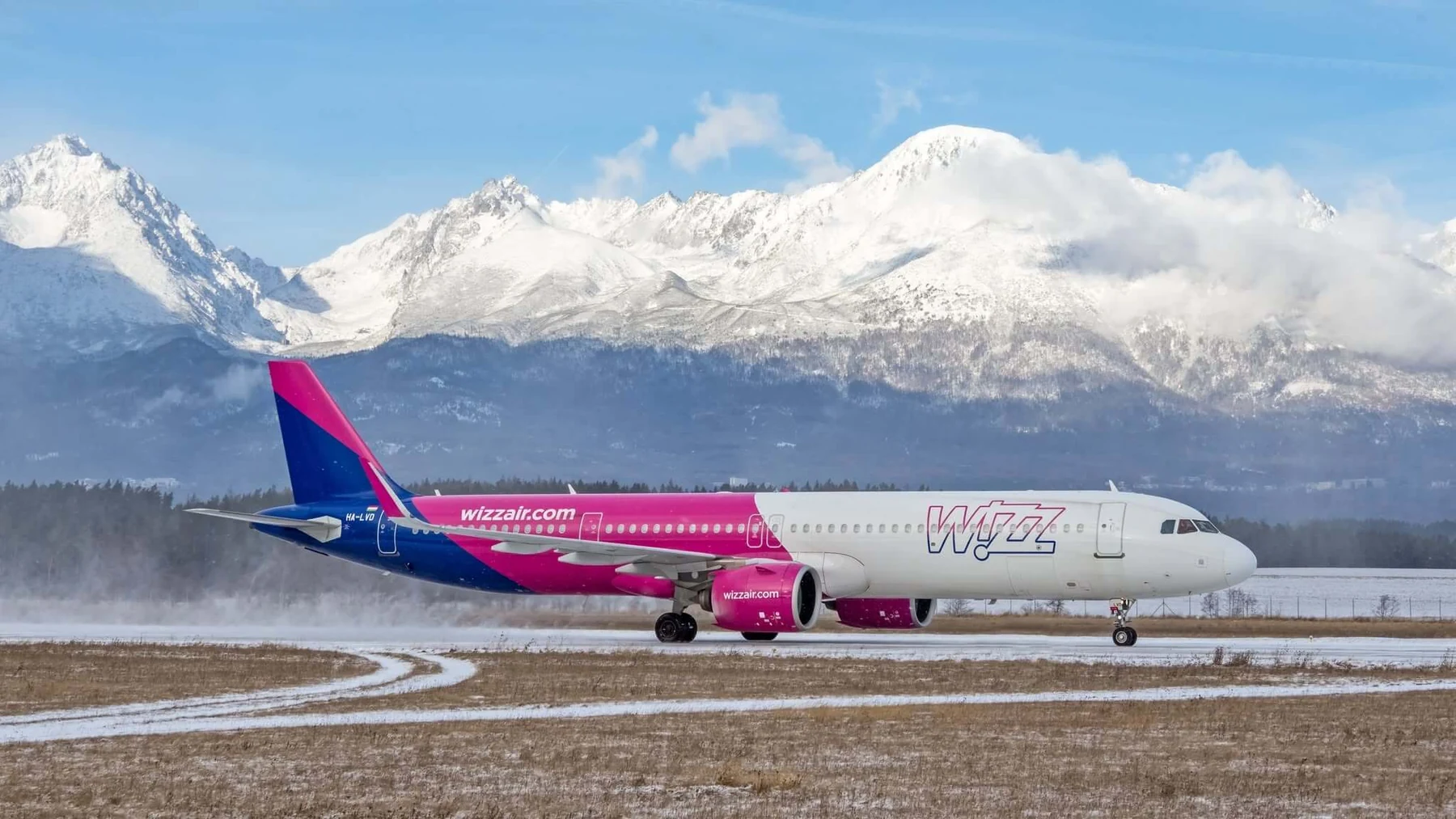 Un Airbus A321 de Wizz Air en la pista del aeropuerto de Poprad-Tatry, con los picos nevados de los Altos Tatras elevándose tras la terminal.