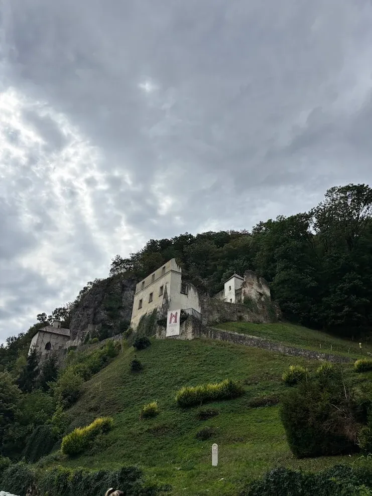 The Skalka pilgrimage site near Trenčín, its white monastery buildings clinging to the rock face above a grassy slope.