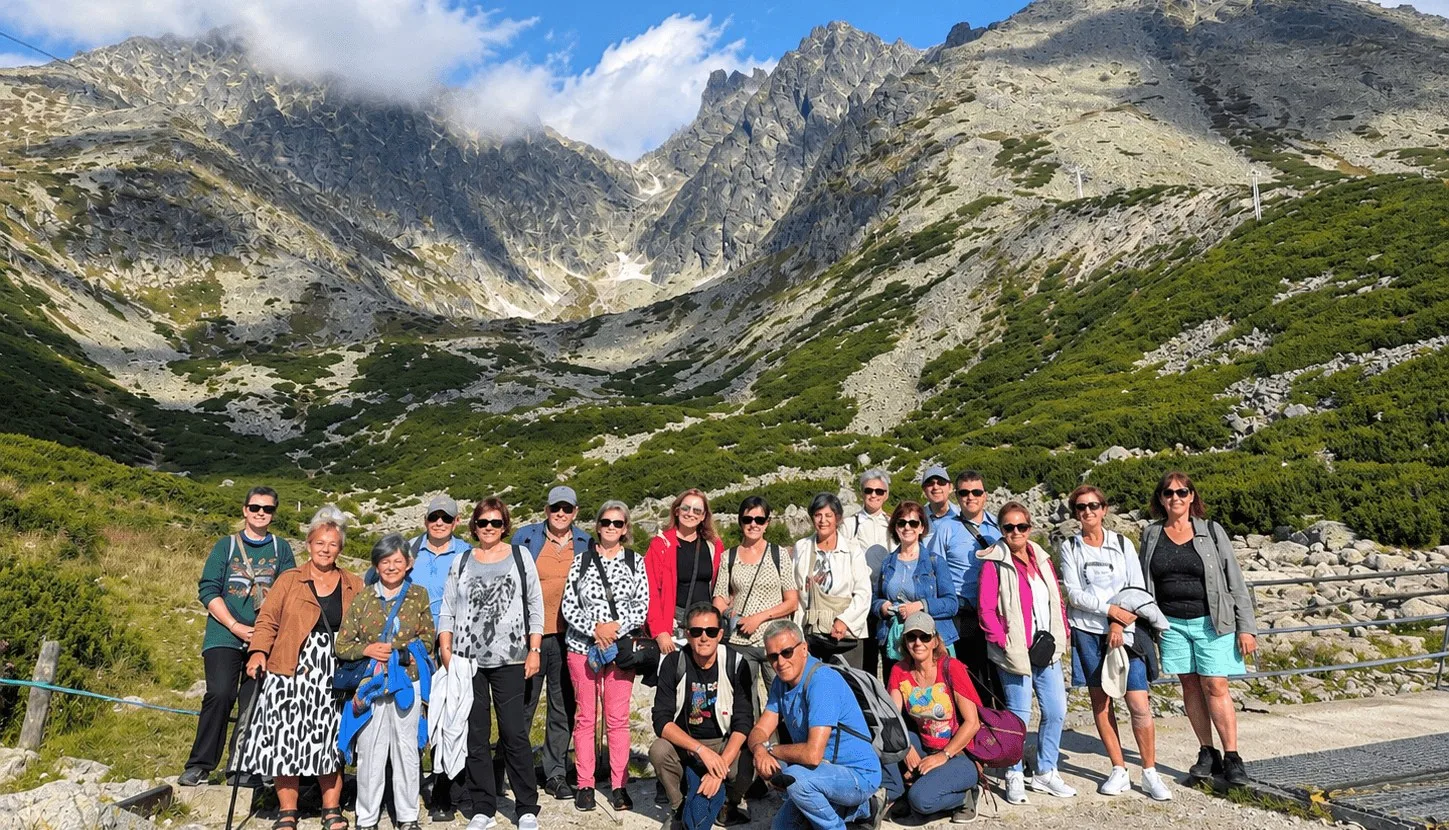 A tour group at Skalnate pleso in Slovakia's High Tatras, with the rocky peaks of the Tatra range rising behind them.