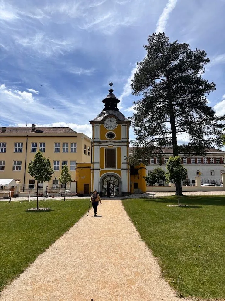 The yellow baroque clock-tower gateway at Spišská Kapitula, a path across the lawn leading up to its arch.