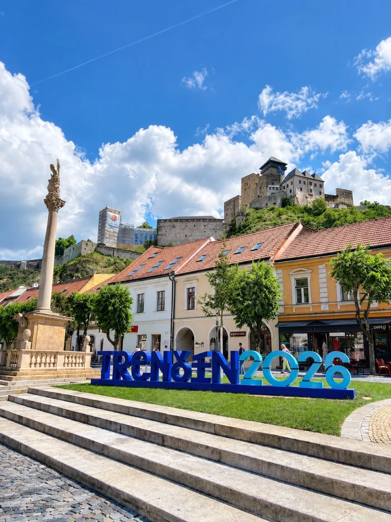 Le panneau TRENCIN 2026 sur la place principale au pied du château de Trenčín, en Slovaquie.