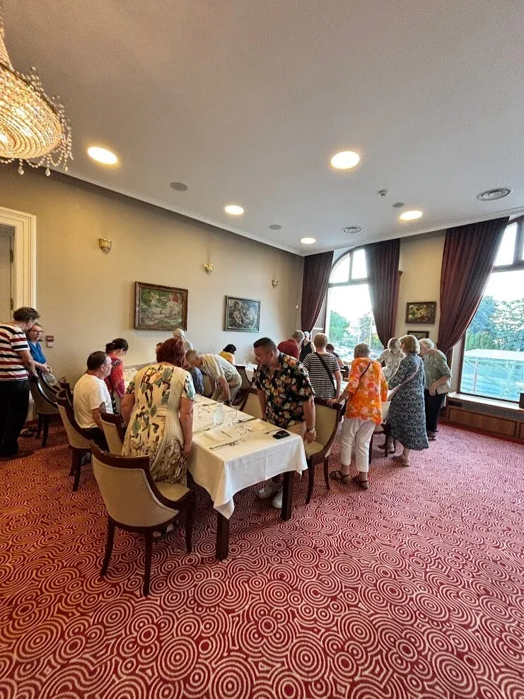 A group taking their seats for lunch in an elegant hotel restaurant in Trenčín, beneath a crystal chandelier.