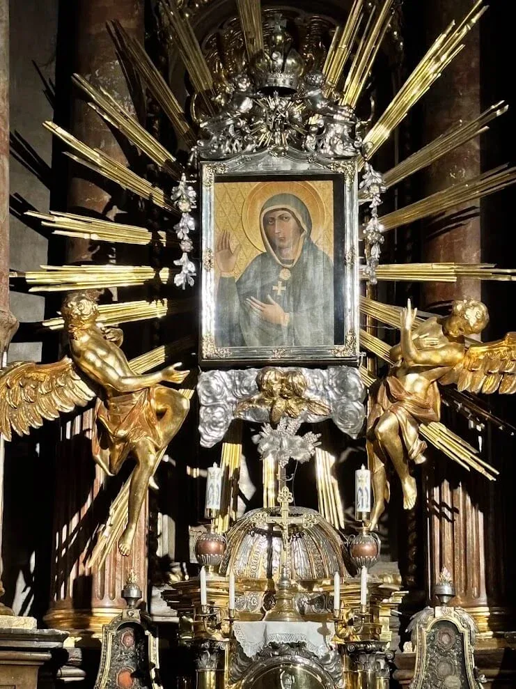 The icon of the Virgin of Trnava in its silver and gilt altar, framed by rays and gilded angels.
