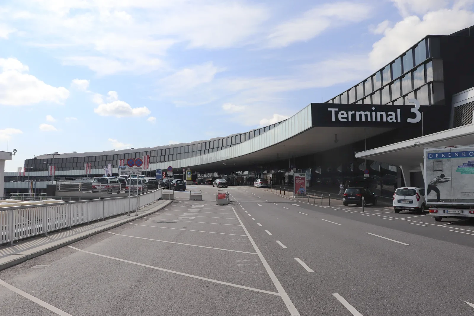 Die Abflugfront von Terminal 3 am Internationalen Flughafen Wien, mit dem geschwungenen Terminalgebäude über der Vorfahrtsstraße.